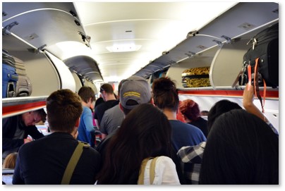 Passengers boarding airplane, overhead bins, carry-on luggage